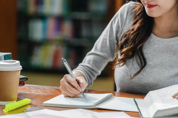 Detailní záběr asijské mladý Student ruční psaní domácí úkol v knihovně — Stock fotografie