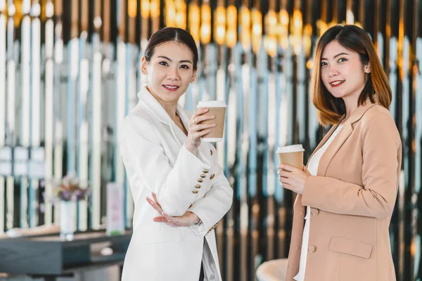 两名亚洲女商人在现代办公室或工作场所喝咖啡时聊天 喝咖啡时休息 放松和下班后聊天 商业和人与人之间的伙伴关系概念 — 图库照片
