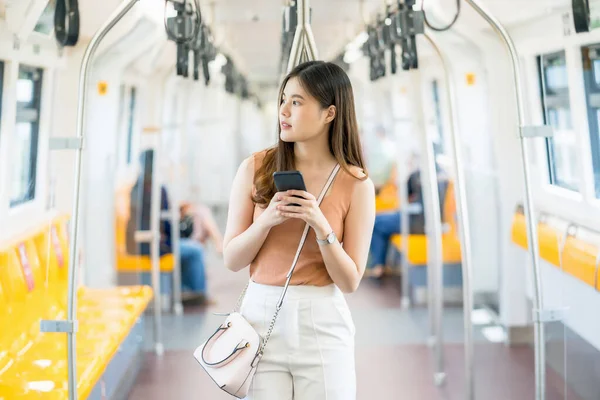 大都市 交通の概念で旅行するとき スマートフォンを使用して地下鉄の列車の外を見て 若いアジアの女性の乗客 — ストック写真