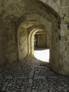 Arnavut kaldırımlı bir cadde ile bir taş kemer ile bakıyor