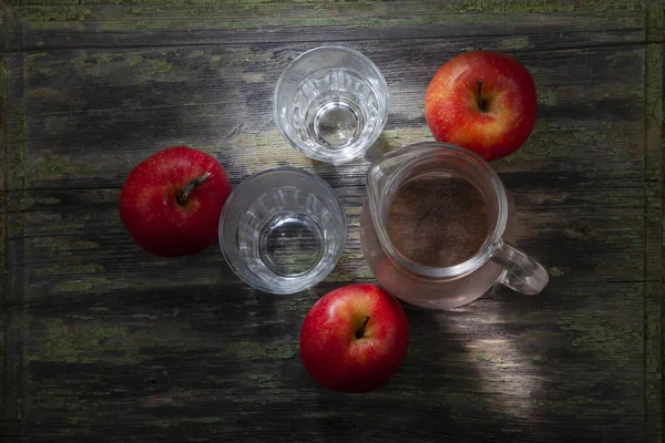 劣化した木製テーブル上のガラス組成物の中で3つの赤いリンゴ意図的に部分的に露出されていない — ストック写真