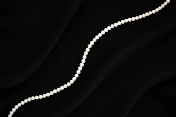 Elegant svart silke bakgrund med vita pärlor halsband. — Stockfoto