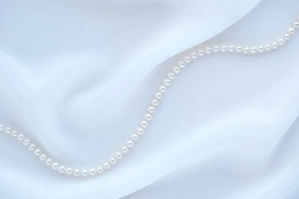 パールネックレスとエレガントな白いシルクの背景. — ストック写真