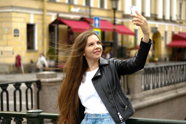 Büyük bir şehrin işlek caddesinde selfie çeken genç bir kadın.. — Stok fotoğraf