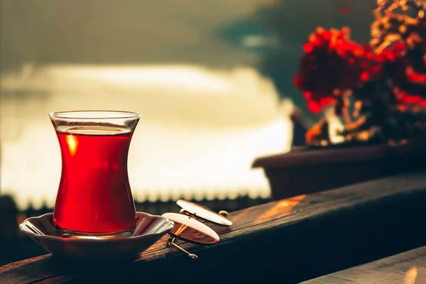 Turkish tea and beautiful sunset at the lake with red flowers background. — Stock Photo, Image