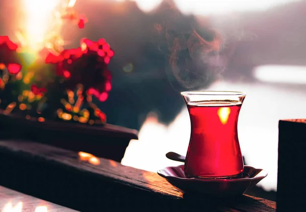 Turkish tea and beautiful sunset at the lake with red flowers background. — Stock Photo, Image