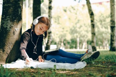 Parkta dijital tablet kullanan mutlu kız