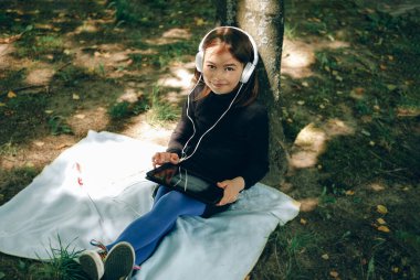 Parkta dijital tablet kullanan mutlu kız