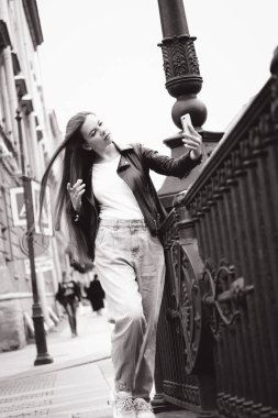 Büyük bir şehrin işlek caddesinde selfie çeken genç bir kadın..