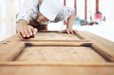 Marangoz zımpara kağıdıyla ahşap işi yapar.