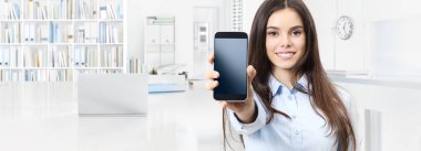 Gülümseyen kadın iç ofis iş arka plan üzerinde izole smartphone gösterir