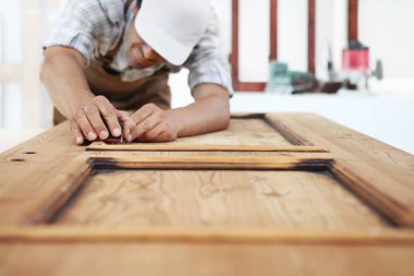 Marangoz zımpara kağıdıyla ahşap işi yapar.