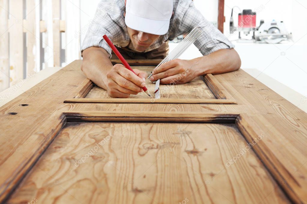 carpenter at work measures with the meter and pencil on wood background
