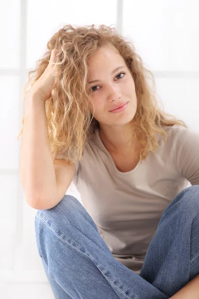 年轻女子的肖像爱抚她的长发 坐在地板上穿着牛仔裤和 T恤衫 Isolared — 图库照片