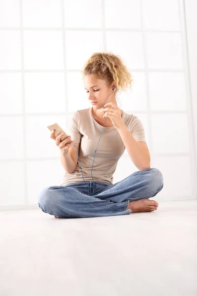 Sitting Young Woman Earphones Cell Phone Curly Hair Dressed Jeans — Stock Photo, Image
