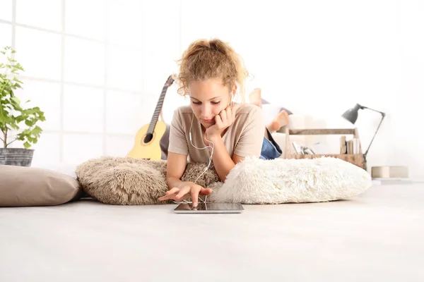 Wanita Muda Yang Cantik Menggunakan Tablet Digital Dengan Earphone Berbaring — Stok Foto