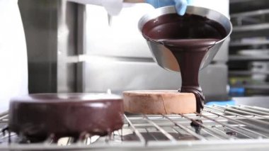 bir paslanmaz çelik endüstriyel mutfak iş üstünde çalışan bir pasta, çikolata sosu, dökme kapak eller pasta şefi hazırlar
