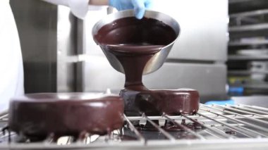 bir paslanmaz çelik endüstriyel mutfak iş üstünde çalışan bir pasta, çikolata sosu, dökme kapak eller pasta şefi hazırlar