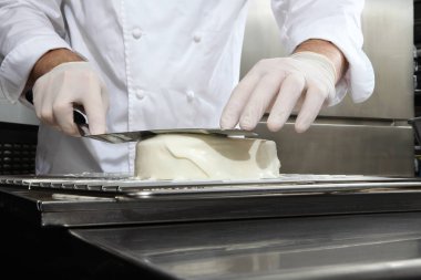 bir paslanmaz çelik endüstriyel mutfak iş üstünde çalışan bir kek, beyaz buzlanma, dökme kapak eller pasta şefi hazırlar