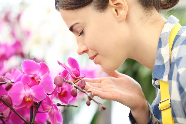 Жінка пахне квітами в саду, ароматом орхідей — стокове фото