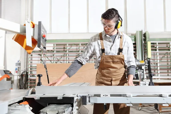 carpenter man work in the joinery, cut a wooden board with circu