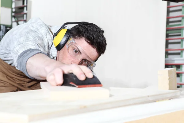 Carpintero hombre trabajo en la carpintería, lijar tablas de madera con — Foto de Stock