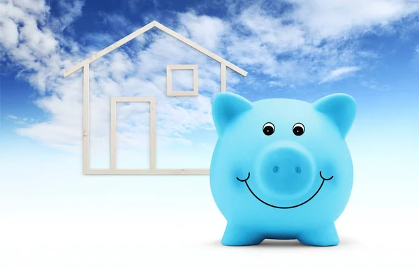 Piggy Bank met houten huis vorm geïsoleerd op blauwe hemel achtergrond — Stockfoto