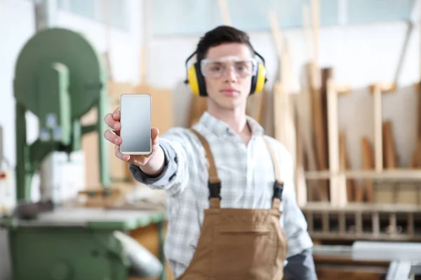 Snickare man visar mobil telefonen isolerad på Snickeri bakgrunds — Stockfoto