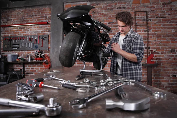 Do it yourself, young man repairing a motorcycle in the garage w — Stock Photo, Image