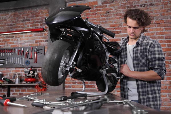 Do it yourself, young man repairing a motorcycle in the garage w — Stock Photo, Image