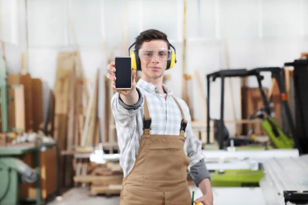 Snickare man visar mobil telefonen isolerad på Snickeri bakgrunds — Stockfoto