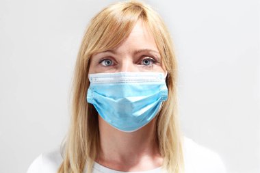 Tıbbi Maskeli Güzel Sarışın Kadın. Yüzünde cerrahi maske olan bir kadının yakın plan portresi, Corona virüsü Covid 19 koruma 