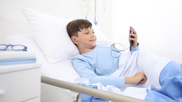 Παιδί Στο Νοσοκομείο Κινητό Τηλέφωνο Και Ακουστικά Ξαπλωμένο Μόνο Στο — Αρχείο Βίντεο