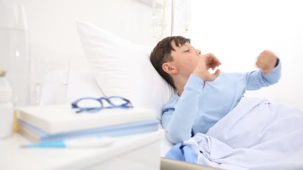 病院の子供は目を覚ますとあくびをしてベッドの上に一人で横たわっている枕に頭を上げる前に — ストック動画