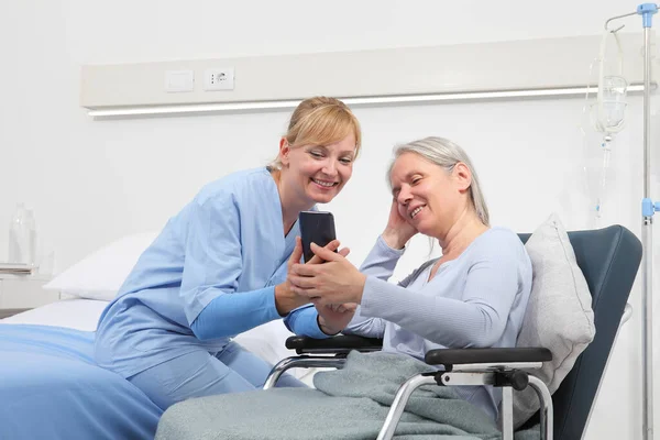 Nurse Helps Cell Phone Contact Elderly Lady Family Wheelchair Bed — Stock Photo, Image