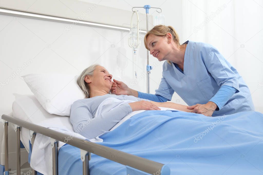 smiling nurse take comfort elderly woman lying in the hospital room bed, by stroking her, concept of loneliness and old age diseases