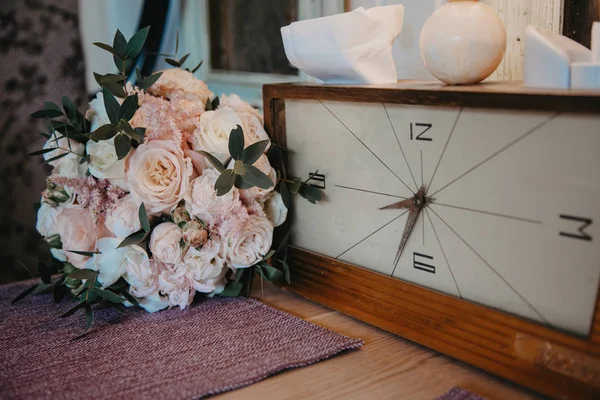 A bouquet of pastel flowers next to the vintage clock on the table. Vintage cafe