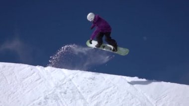 Ağır çekim: büyük dağ kar Park'ta yarım boru sürme, yüksek halfpipe duvardan atlama, hile ve rotasyonlar kapmak ile güneşli kışın gerçekleştirme genç pro snowboarder