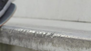 Ağır çekim Dof aşırı yakından: atlama ve sokakta beton bankta sürgülü tanınmaz kaykaycı. Patencinin kaykay bacaklar ve hile bir şehirde kaykay ile taşlama iş closeup