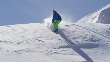 Ağır çekim yakın çekim: güneşli dağ backcountry kar püskürtme toz sürme ve toz döner, yapıyor Extreme snowboard. Eğleniyor snowboard bakırlı taze kar snowboard