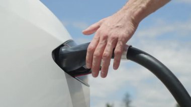 Kadar yakın, ağır çekim: şarj istasyonu üzerinden tanınmaz işadamı bitirdiğinden elektrikli araba. Lüks beyaz elektrik Tesla araba dolu. Elektrik dolum rekabet ve kablo bağlantısı kesildi