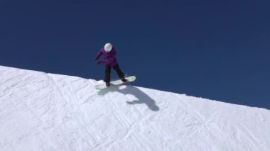Ağır çekim: büyük dağ kar Park'ta yarım boru sürme, yüksek halfpipe duvardan atlama, hile ve rotasyonlar kapmak ile güneşli kışın gerçekleştirme genç pro snowboarder