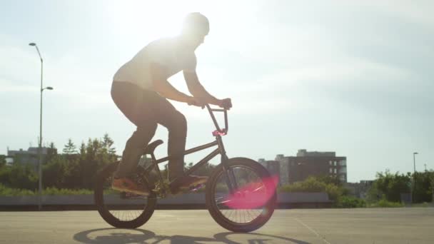 スローモーションをクローズ アップ 極端な Bmx バイク日当たりの良い公園に乗って美しい夏の日に Bmx の自転車とノーリー尾鞭トリックを停止します クールな若い Bmx バイク街にトリックを実行します — ストック動画
