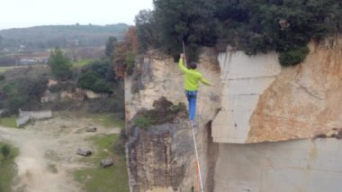 Hava, yakın: aşırı highliner terk edilmiş ocağında kayalık duvarlar arasında gerilmiş highline yürüyüş yukarıda uçan. Rocky Kanyon, longline Dengeleme üzerinde slacklining emniyet kemeri ile genç adam