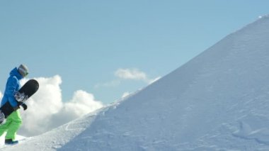 Ağır çekim yakın çekim: aşırı snowboard kışın yokuş yukarı doğru dağ Zirvesi taze toz karda hiking. Freeride snowboard deki dağın backcountry dağ kayak merkezinde tırmanma