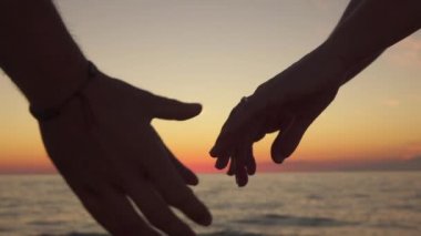 Ağır çekim yakın çekim: Sevgi dolu ve erkek yukarı bakan el bakımı ve gelecekteki eşi tutarak. Kız aşağı dönük avuç içi, handholding sıkıca samimi arkadaşı rüya gibi okyanus, günbatımında desteklemek