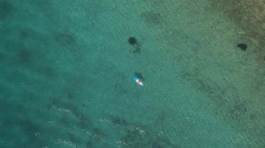 Hava: yüksek paddleboarding güzel berrak turkuaz tropikal deniz kızı binici ayağa yukarıda uçan. Çarpıcı kayalık, taşlık ve kumlu deniz dibinin açığa şeffaf suda parlayan güneş