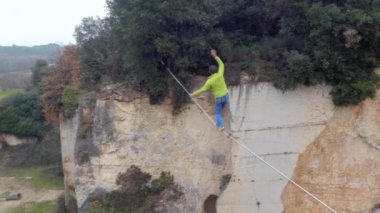 Hava, yakın: aşırı highliner terk edilmiş ocağında kayalık duvarlar arasında gerilmiş highline yürüyüş yukarıda uçan. Rocky Kanyon, longline Dengeleme üzerinde slacklining emniyet kemeri ile genç adam