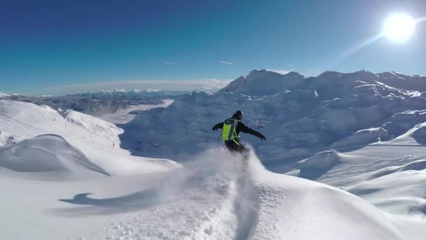 跟随特写 快乐的滑雪板有乐趣滑雪在一个阳光明媚的冬日在雪山 极端随心所欲滑雪板骑新鲜粉雪背道而驰山滑雪胜地 — 图库视频影像