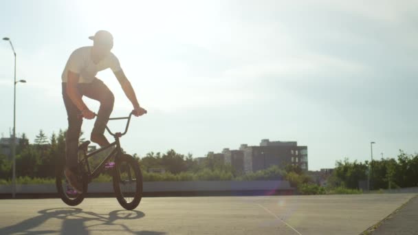 スローモーションをクローズ アップ 極端な Bmx バイク日当たりの良い公園に乗って美しい夏の日に Bmx の自転車とノーリー尾鞭トリックを停止します クールな若い Bmx バイク街にトリックを実行します — ストック動画